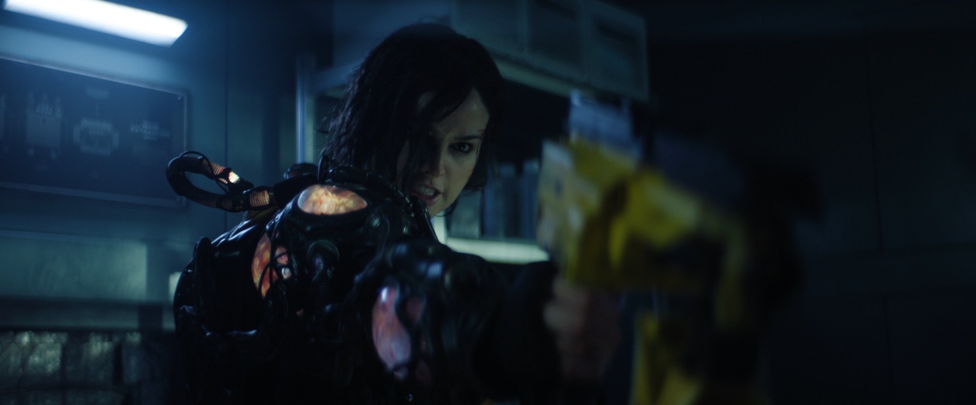 A woman (Eiza González) holding a yellow weapon while wearing a glowing bio-organic space suit in Ash.